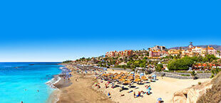 Helderblauwe zee met strand en kust van Tenerife