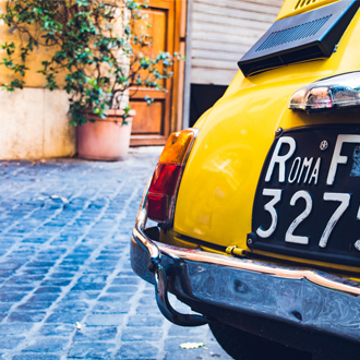 Een-oude-gele-auto-met-een-nummerbord-van-Rome-in-de-straten-van-Rome