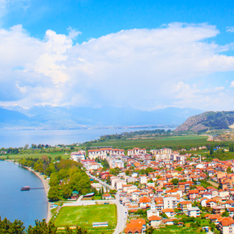 De kust van Ohrid in Macedonie met natuurlandschap en huizen met oranje daken