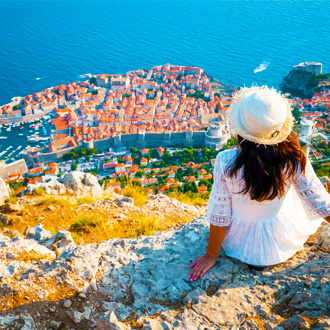 Vrouw-op-de-rand-van-een-klif-met-uitzicht-op-Dubrovnik-Midden-Dalmatie