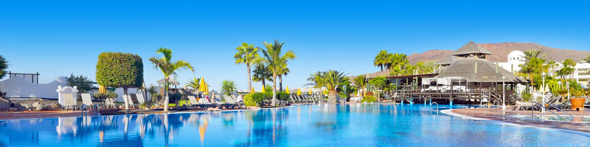 All Inclusive resort met groot zwembad, ligbedjes en palmbomen op Lanzarote