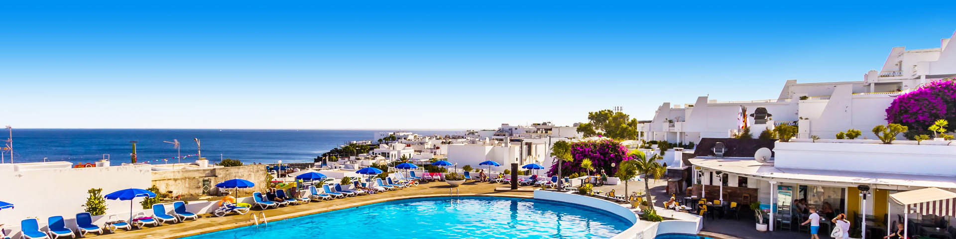 Een blauw zwembad en witte huisjes in Puerto del Carmen