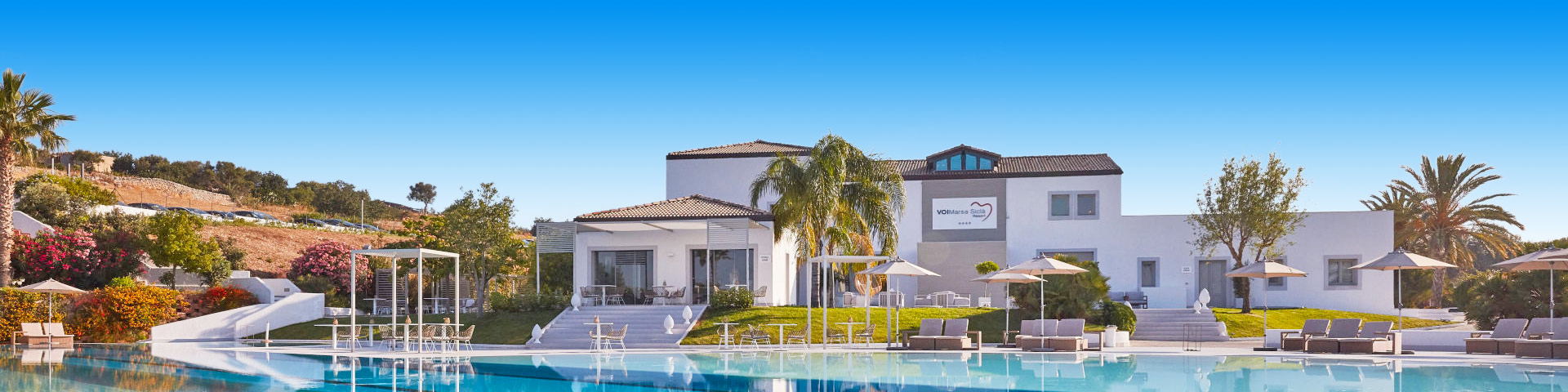 Wit hotel met zwembad en palmbomen in Italië