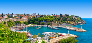 Haven met boten, omringd door historische gebouwen en groene heuvels, Antalya, Turkije.