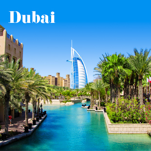 Burj Al Arab in Dubai onder blauwe lucht, omringd door palmbomen en kanaal.