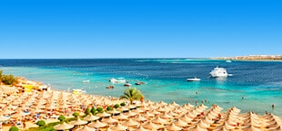 Strand in Egypte met parasols en azuurblauwe zee