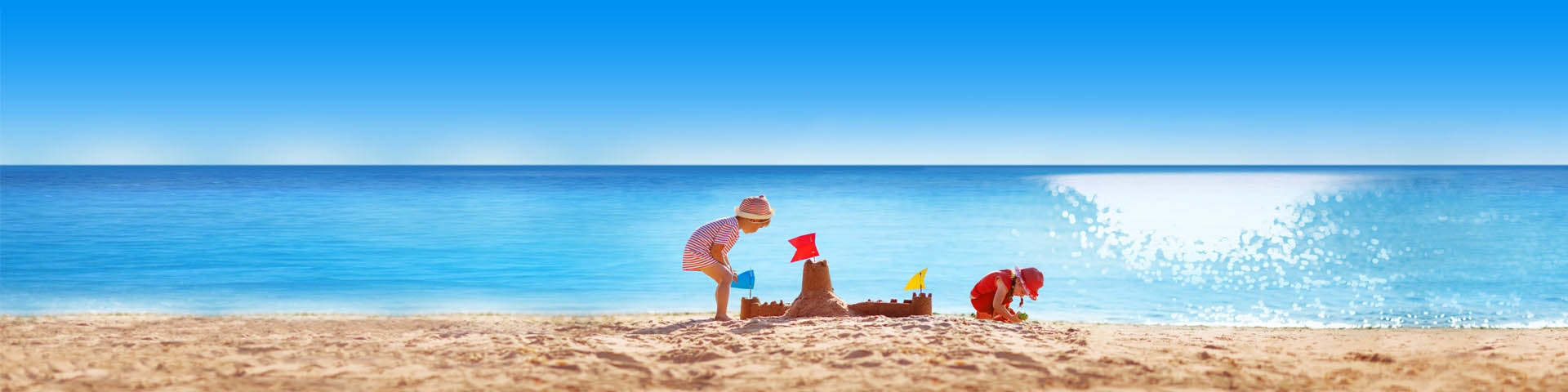 Kinderen spelen op het strand met een azuurblauwe zee als achtergrond