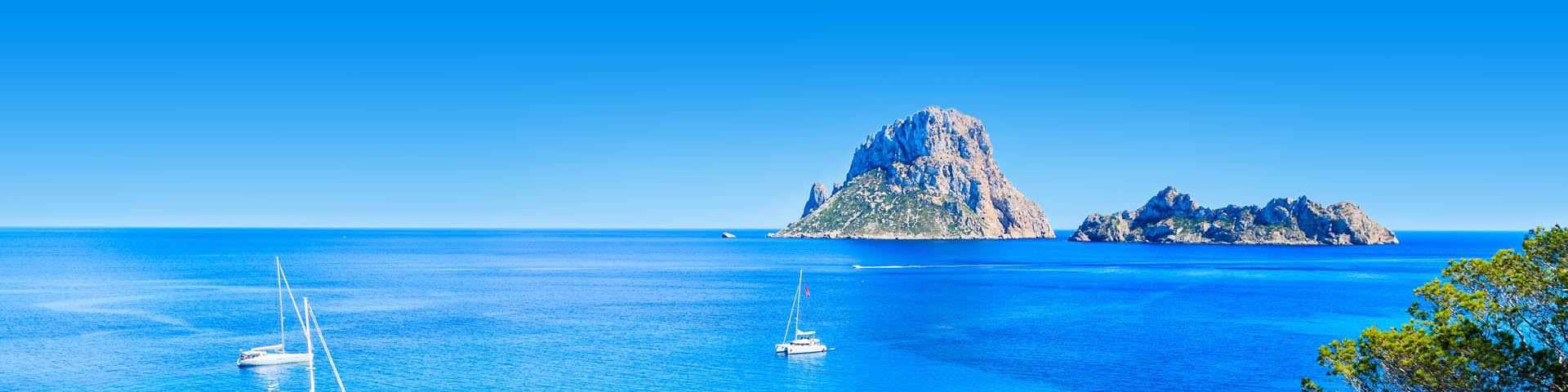 Kustlijn van Ibiza met helderblauw zeewater en een bootje op de voorgrond