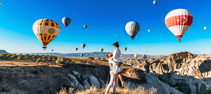 Verliefd koppel met schitterend uitzicht op de luchtballonnen boven Cappadocië