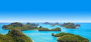 Helderblauwe zee met verschillende kleine bergen in Thailand