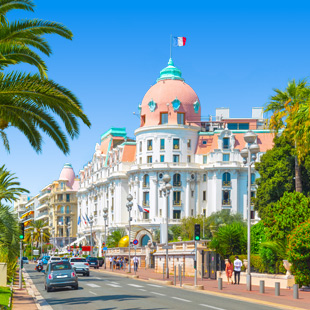 Uitzicht op Nice met de Promenade des Anglais, een lange kustlijn met strand, helderblauwe zee en bebouwing langs de boulevard.