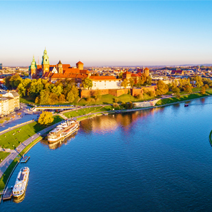 Uitzicht op de Wisła-rivier in Krakau met een brug over het water, groene oevers en historische gebouwen langs de kade.