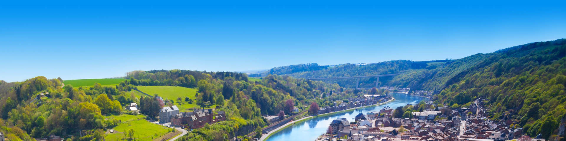 Uitzicht over groen heuvelachtig landschap met rivier dat door een stad loopt in België