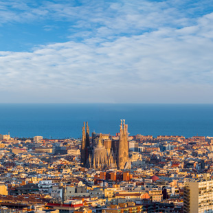 Sagrada Familia in Barcelona met hoge torens en omliggende stad, gezien van boven met straten en gebouwen rondom de basiliek.
