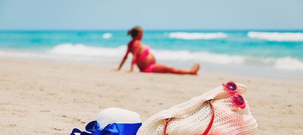 Zwangere vrouw in bikini op het strand
